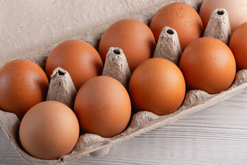 Fresh brown eggs in a cardboard carton arranged on a light wooden surface showcasing a farm-fresh collection ready for cooking