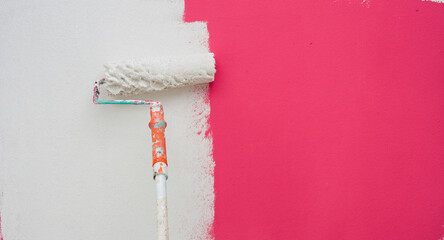 A paint roller is painting with white and orange pink teindoors