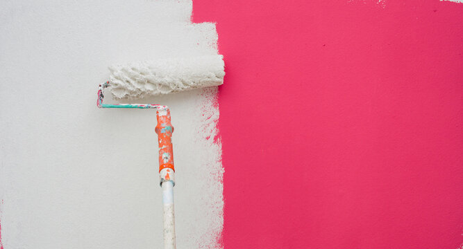 A paint roller is painting with white and orange pink teindoors