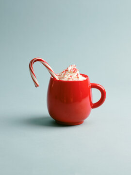 Festive red mug filled with creamy holiday drink and candy cane