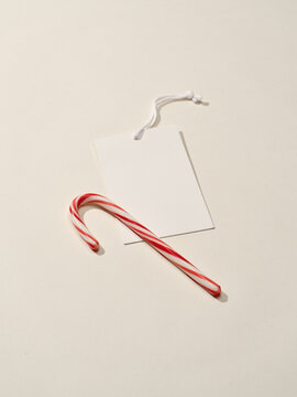 Festive candy cane alongside a blank gift tag on a light background