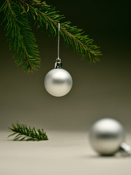 Silver ornament hanging from a pine branch during the holidays