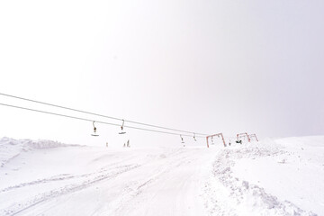 Ski lift empty ropeway,gondola on hilghland alpine resort.chairlift cable way.skiing and snowboarding.mountain peaks covered in snow landscape. Winter leisure sport,recreation,travel