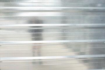 Shiny silver metal wall fence with reflection of human figure