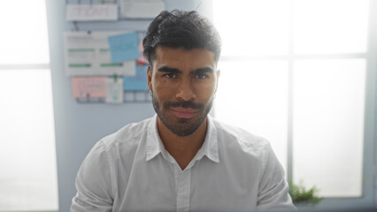 Young, hispanic, man working in office environment with focus on attractive appearance and serious expression
