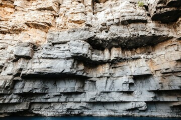 Layers of sedimentary rock cliff rise from blue waters of Kaiser Franz Joseph fjord in Northeast Greenland National Park