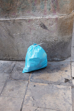 Bright blue plastic bag in a corner of concrete wall urban city 