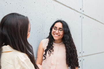 Two Women Friends Talking and Leaning on a Wall