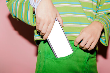 Woman putting smartphone with blank screen in green jeans pocket