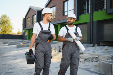 A team of professional builders stand near the newly built cottages. Townhouse