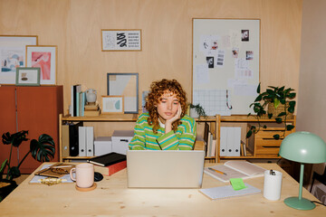 Bored woman working at laptop in her home office