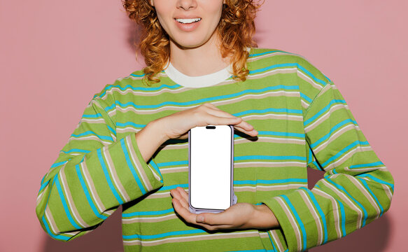 Woman showing smartphone with blank screen on pink background