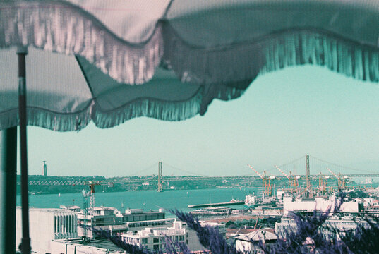 Lisbon riverside view with bridge and umbrellas in foreground
