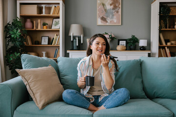 Woman Relaxing on Sofa with Coffee and Smartphone at Home