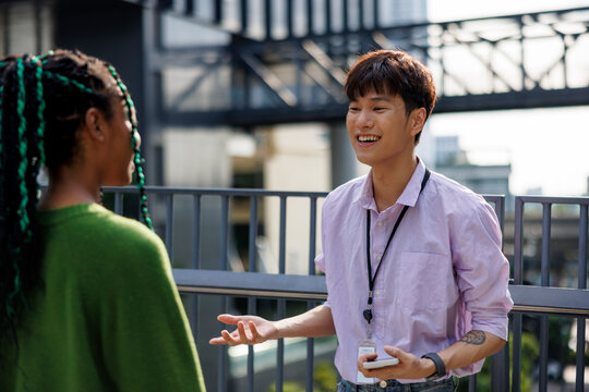 Cheerful diverse male and female colleagues discussing outdoors