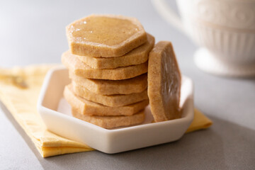 Honey Shortbread Cookies, Biscuits, cut into hexagon shape, on a plate with napkin and teacup
