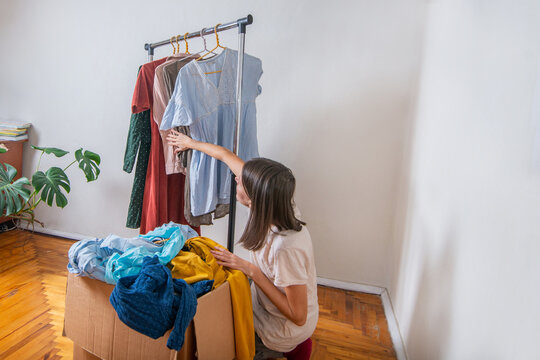 Woman sorting out used clothes in the wardrobe for swap