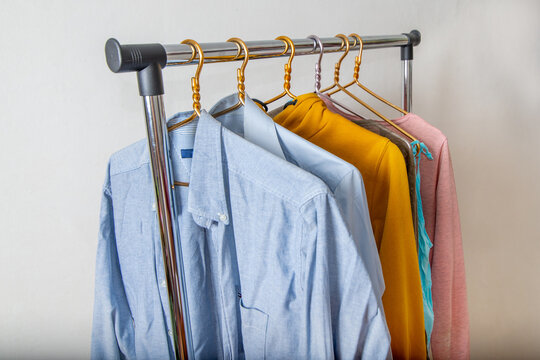 Various men's and women's clothing on a clothing rail