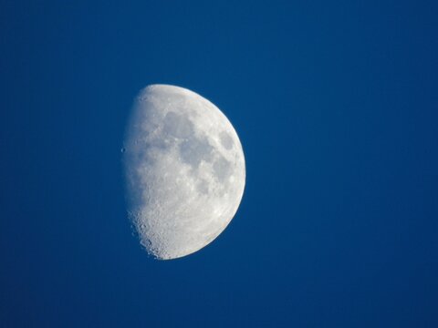 Waxing gibbous moon with craters in blue sky