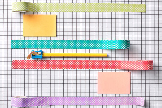 Colorful Stationery and Tape Arranged On Grid Background