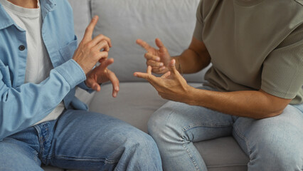 Two men sitting together and using sign language, highlighting a loving relationship in a living room setting, symbolizing family and communication within the lgbtq community.