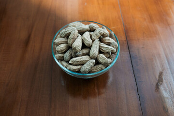 Organic Raw Peanuts in a glass Bowl on the wooden table, healthy snack