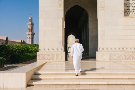 Omani man walking up stairs at sultan qaboos grand mosque