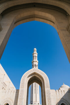 Sultan qaboos grand mosque minaret emerging from arched gateways