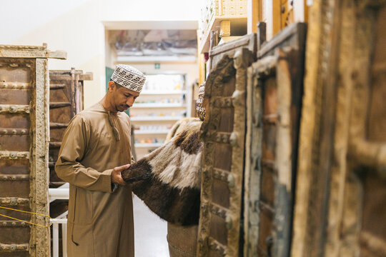 Omani merchant examining traditional goods in a market