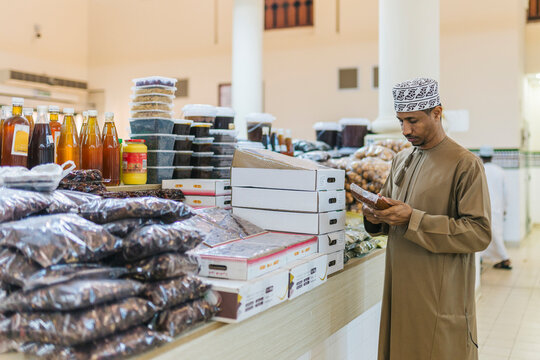 Omani vendor examining product in traditional market stall