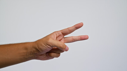 Man's hand showing a peace sign against a plain background symbolizing peace and unity in a minimalist setting.