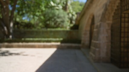 Blurred outdoor scene in mallorca, spain, featuring defocused architecture, greenery, stone walls, and sunny weather.