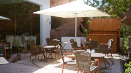 Outdoor cafÃ© in lanzarote with blurred background featuring empty wicker chairs and tables under an umbrella