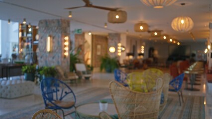 Defocused hotel lobby highlighting empty chairs and lit ambiance with bright bokeh lights in the...