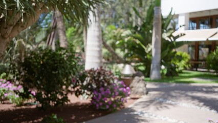 Blurred background of a tropical resort garden with vibrant flowers, palm trees, and lush greenery.