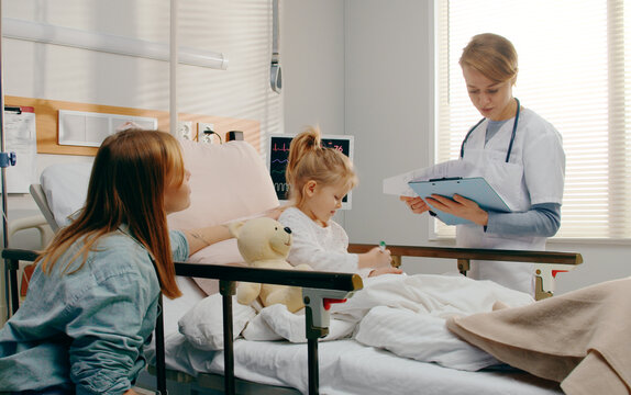 Doctor visiting little girl patient and her mother in hospital room