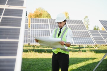 Portrait of a successful businessman or engineer inspecting the operation of solar panels. The concept of green energy