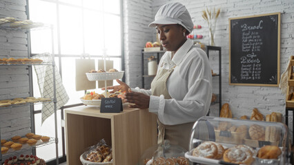 African american woman working in a bakery arranging gluten-free pastries on display in a modern...