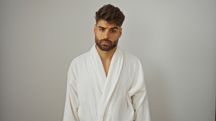 Handsome young hispanic man with a beard posing over an isolated white background wearing a bathrobe