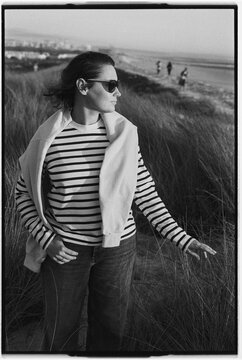 Woman in striped shirt standing on a dune overlooking a coastal 