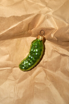 Glossy Xmas tree toy in the shape of a cucumber on wrapping paper.