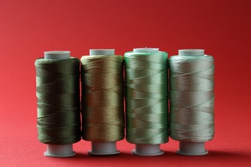 Spools of colorful sewing threads on red background