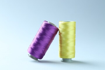 Spools of colorful sewing threads on light background