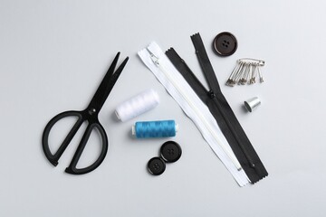 Different sewing supplies on white background, flat lay