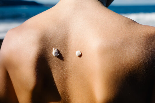 Naked back of an anonymous young woman with sunscreen body cream
