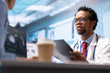 Male physician doing an x ray diagnostics scan interpretation during check up visit, discussing...
