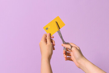 Person Cutting Credit Card with Scissors on Purple Background