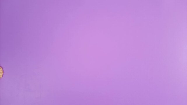 Looping stop motion cookies forming heart shape. Transformation of cookie arrangement into heart on purple background, Valentine's Day, symbol of love and romance.