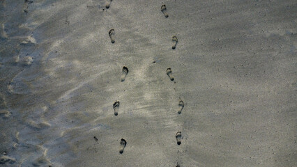 Footprints in black sand seen from above