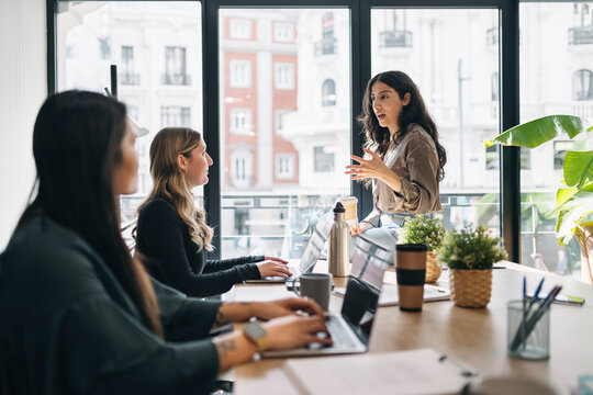 Team discussion with focus on leader woman in a bright office